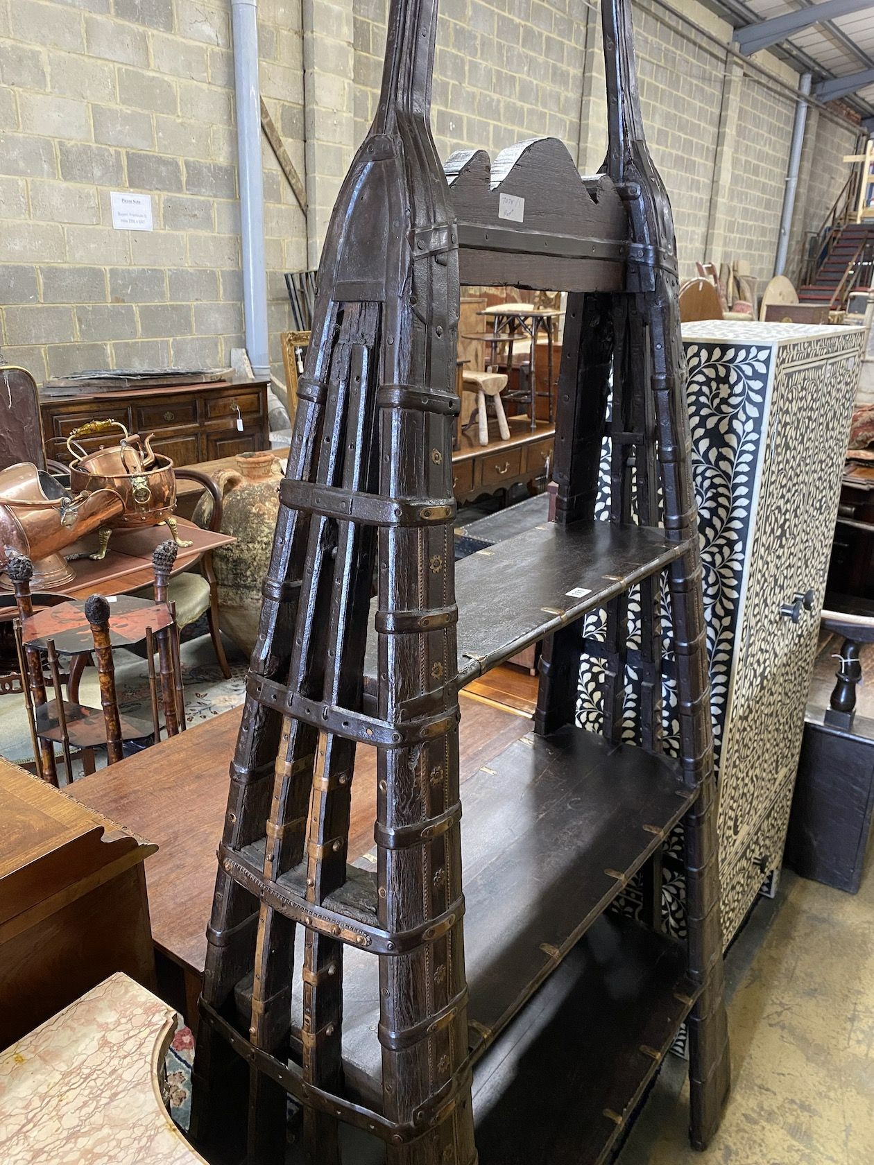 An Indian brass mounted carved hardwood three tier shelf unit, constructed from a 19th century ox harness, length 106cm, depth 40cm, height 202cm
